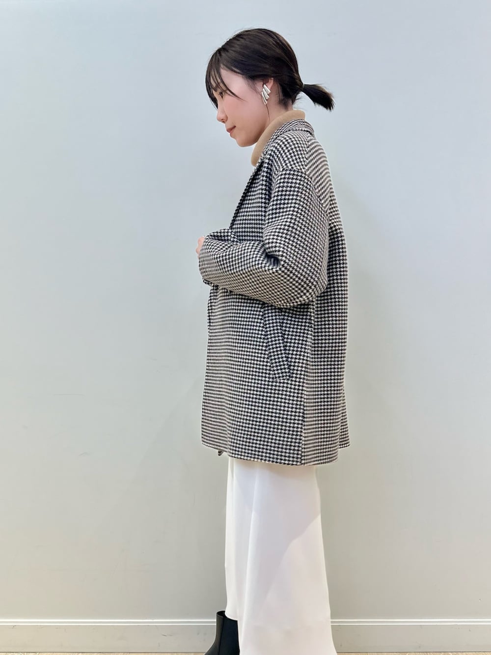 ベージュ系のチェスターコート、ホワイト系のスカート、イエロー系のニット/セーターを着用したレディースの冬コーディネートの4枚目の写真