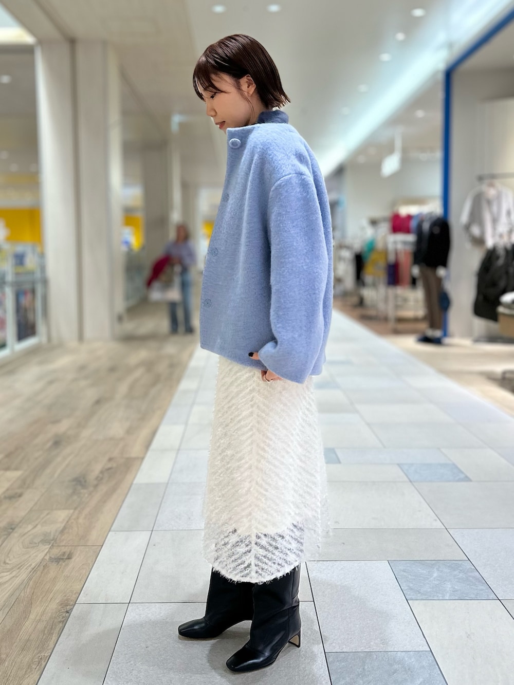 ブルー系のその他アウター、ホワイト系のスカート、ブラック系のブーツを着用したレディースの冬コーディネートの3枚目の写真