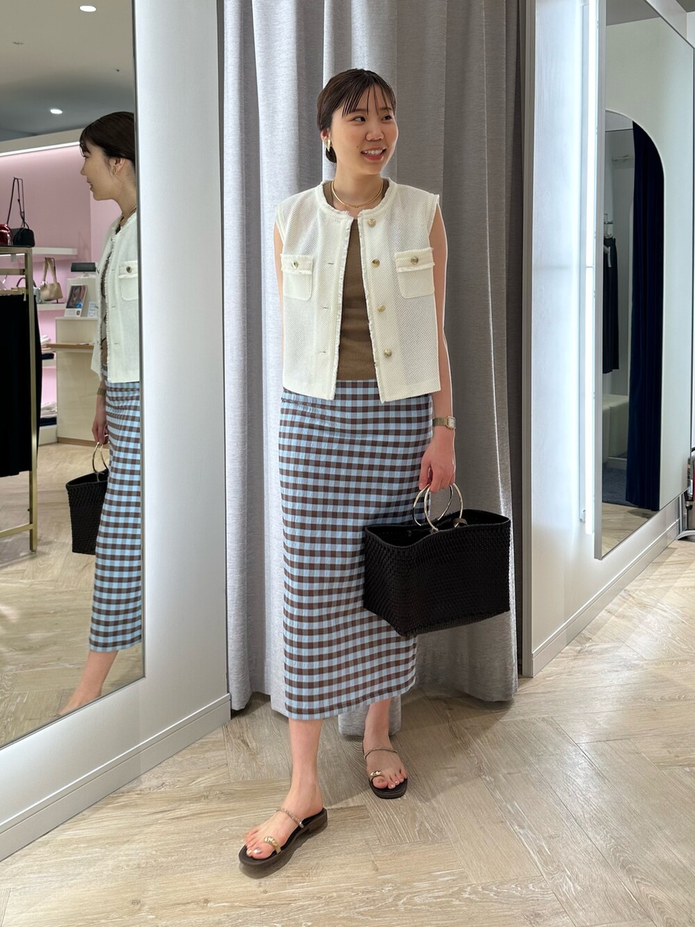 ブラウン系のかごバッグ、ブラウン系のスカート、ホワイト系のベストを着用したレディースの夏コーディネートの6枚目の写真