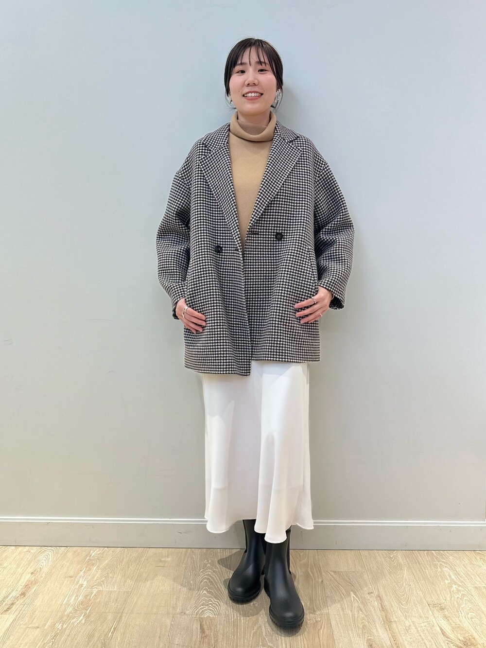 ベージュ系のチェスターコート、ホワイト系のスカート、イエロー系のニット/セーターを着用したレディースの冬コーディネートの6枚目の写真