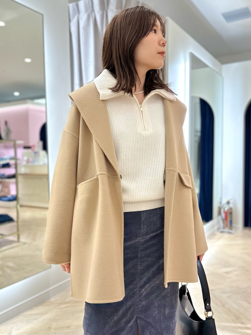 イエロー系のダッフルコート、グレー系のスカート、ホワイト系のニット/セーターを着用したレディースの秋コーディネートの3枚目の写真