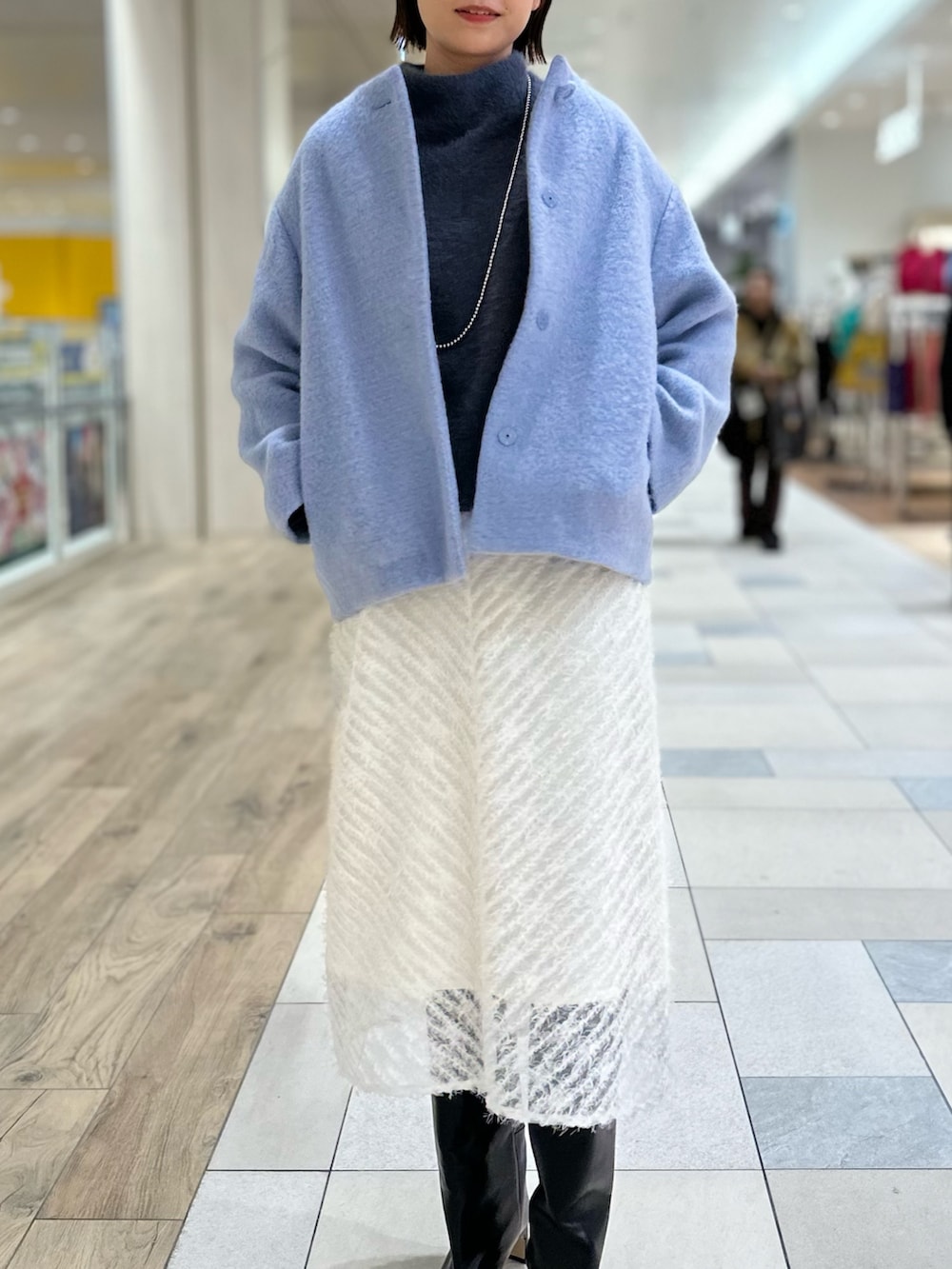 ブルー系のその他アウター、ホワイト系のスカート、ブラック系のブーツを着用したレディースの冬コーディネートの4枚目の写真