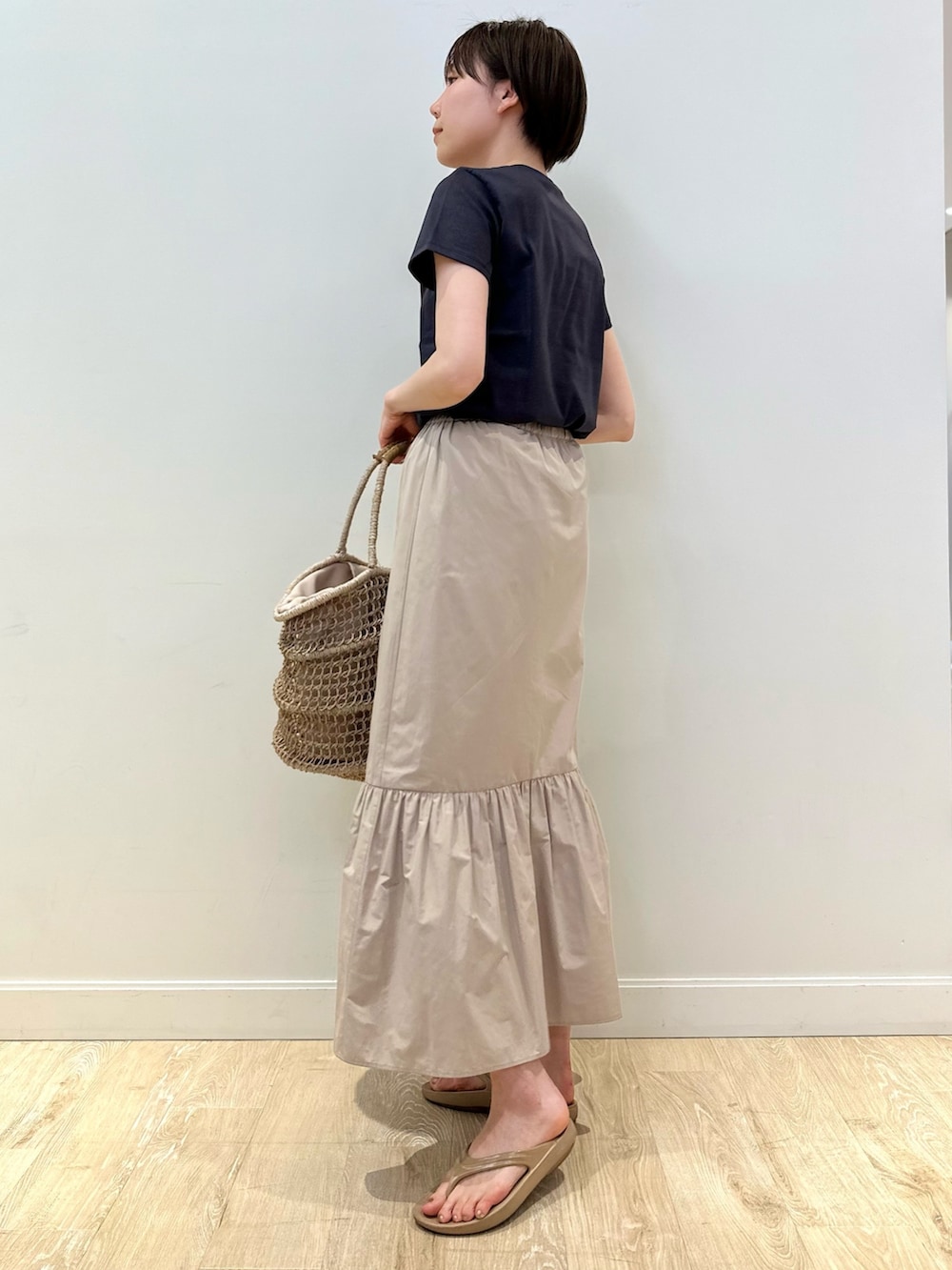 グレー系のTシャツ/カットソー、ベージュ系のスカート、ベージュ系のかごバッグを着用したレディースの夏コーディネートの3枚目の写真