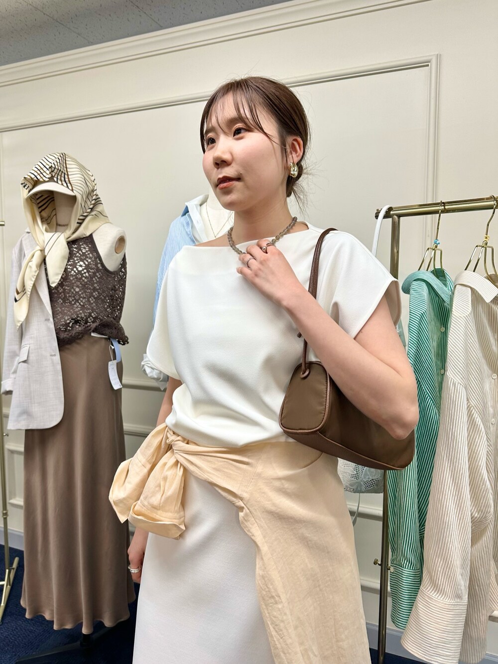 ホワイト系のスカート、オレンジ系のシャツ/ブラウス、ブラウン系のショルダーバッグを着用したレディースの春コーディネートの3枚目の写真