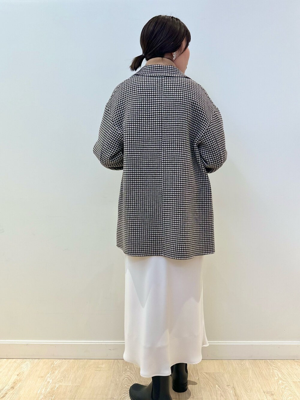 ベージュ系のチェスターコート、ホワイト系のスカート、イエロー系のニット/セーターを着用したレディースの冬コーディネートの5枚目の写真