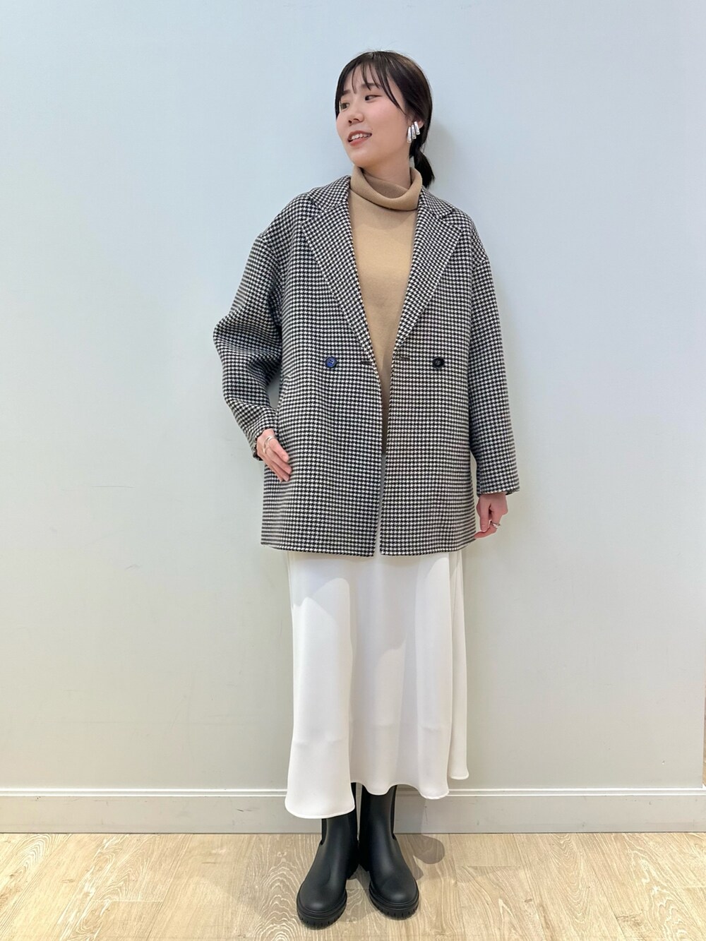 ベージュ系のチェスターコート、ホワイト系のスカート、イエロー系のニット/セーターを着用したレディースの冬コーディネートの2枚目の写真