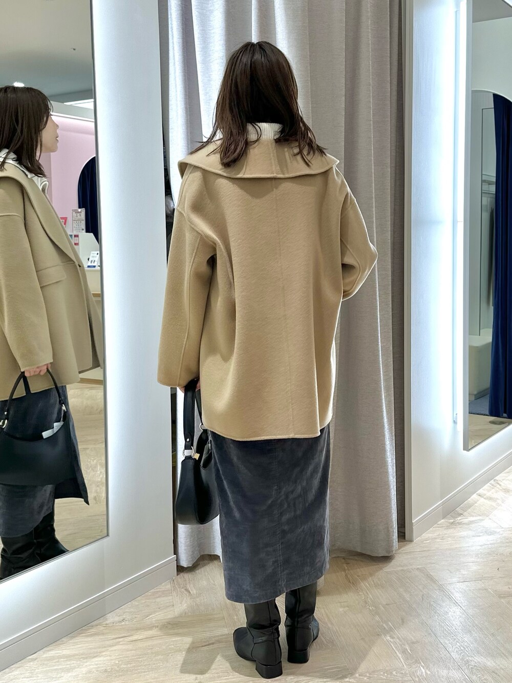 イエロー系のダッフルコート、グレー系のスカート、ホワイト系のニット/セーターを着用したレディースの秋コーディネートの4枚目の写真