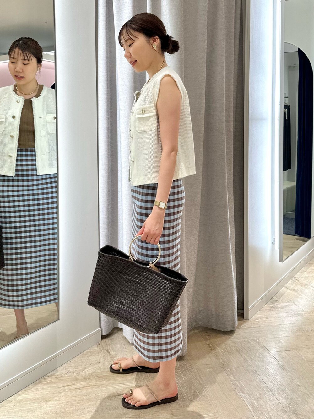 ブラウン系のかごバッグ、ブラウン系のスカート、ホワイト系のベストを着用したレディースの夏コーディネートの2枚目の写真