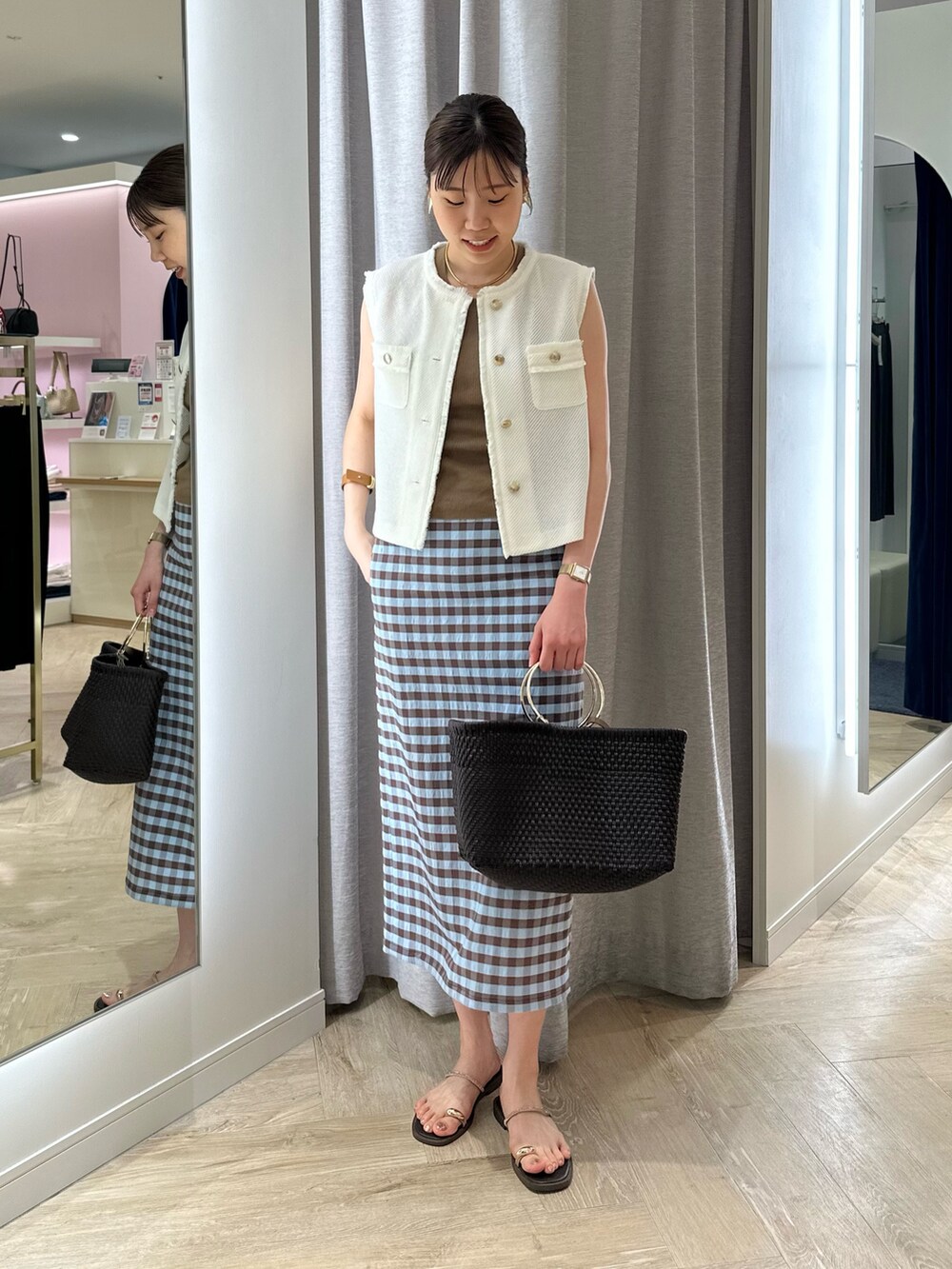 ブラウン系のかごバッグ、ブラウン系のスカート、ホワイト系のベストを着用したレディースの夏コーディネートの7枚目の写真