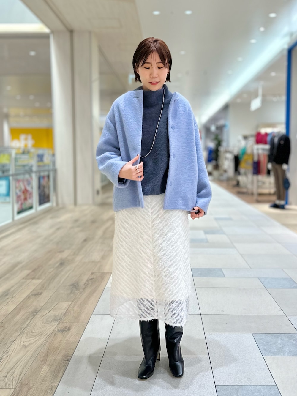 ブルー系のその他アウター、ホワイト系のスカート、ブラック系のブーツを着用したレディースの冬コーディネートの2枚目の写真