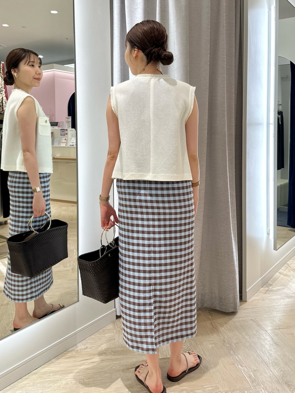 ブラウン系のかごバッグ、ブラウン系のスカート、ホワイト系のベストを着用したレディースの夏コーディネートの3枚目の写真