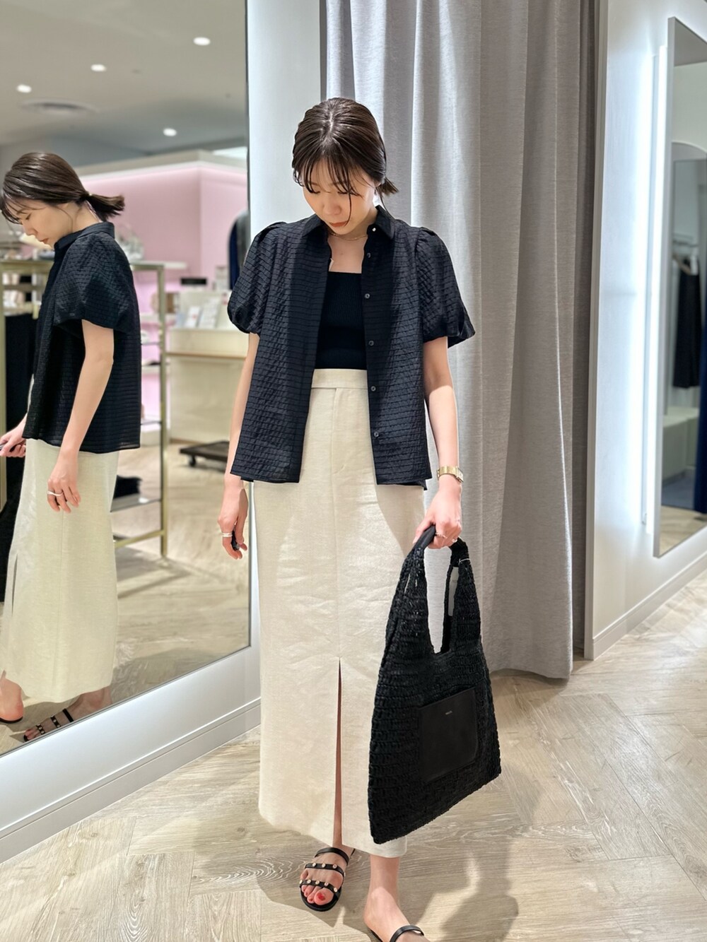 ベージュ系のスカート、ブラック系のシャツ/ブラウス、ブラック系のかごバッグを着用したレディースの夏コーディネートの2枚目の写真