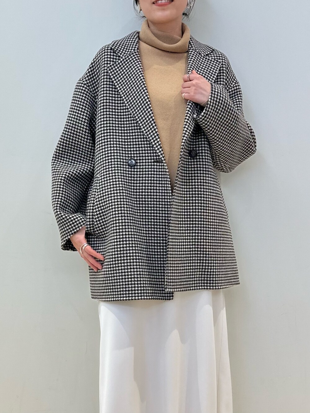 ベージュ系のチェスターコート、ホワイト系のスカート、イエロー系のニット/セーターを着用したレディースの冬コーディネートの3枚目の写真