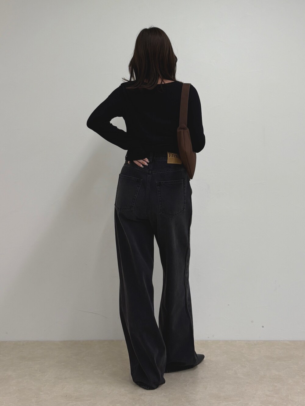 ブルー系のデニムパンツ、ブラック系のTシャツ/カットソー、ブラウン系のショルダーバッグを着用したレディースの夏コーディネートの3枚目の写真