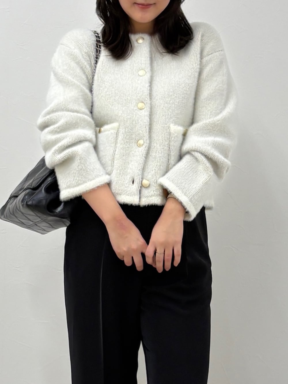 ブラック系のスラックス、ホワイト系のカーディガン/ボレロを着用したレディースの秋コーディネートの3枚目の写真