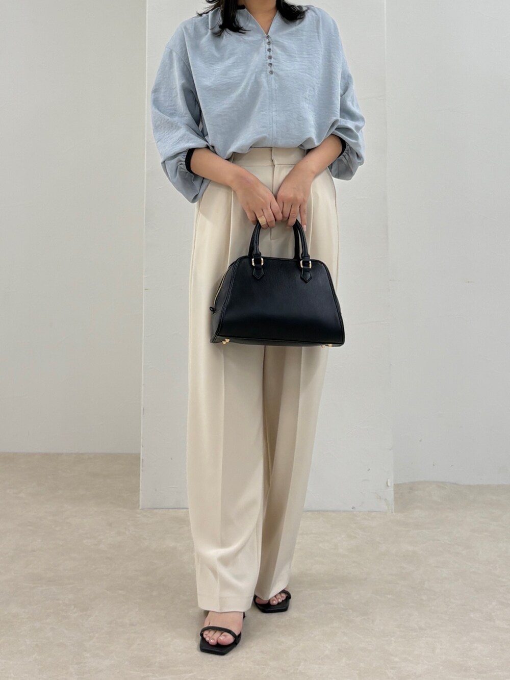 ブルー系のシャツ/ブラウス、ホワイト系のスラックス、ブラック系のショルダーバッグを着用したレディースの秋コーディネートの3枚目の写真