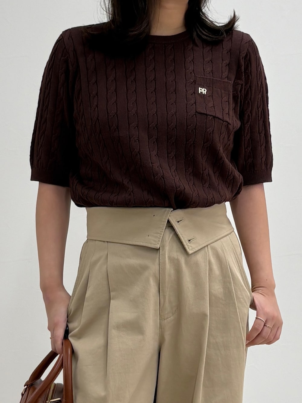 ブラウン系のニット/セーター、ベージュ系のチノパンツ、イエロー系のショルダーバッグを着用したレディースの夏コーディネートの4枚目の写真