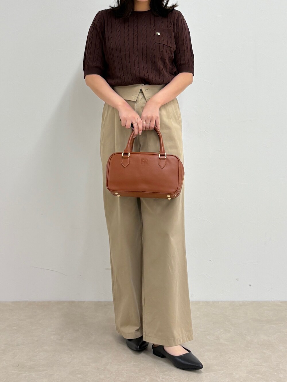 ブラウン系のニット/セーター、ベージュ系のチノパンツ、イエロー系のショルダーバッグを着用したレディースの夏コーディネートの2枚目の写真