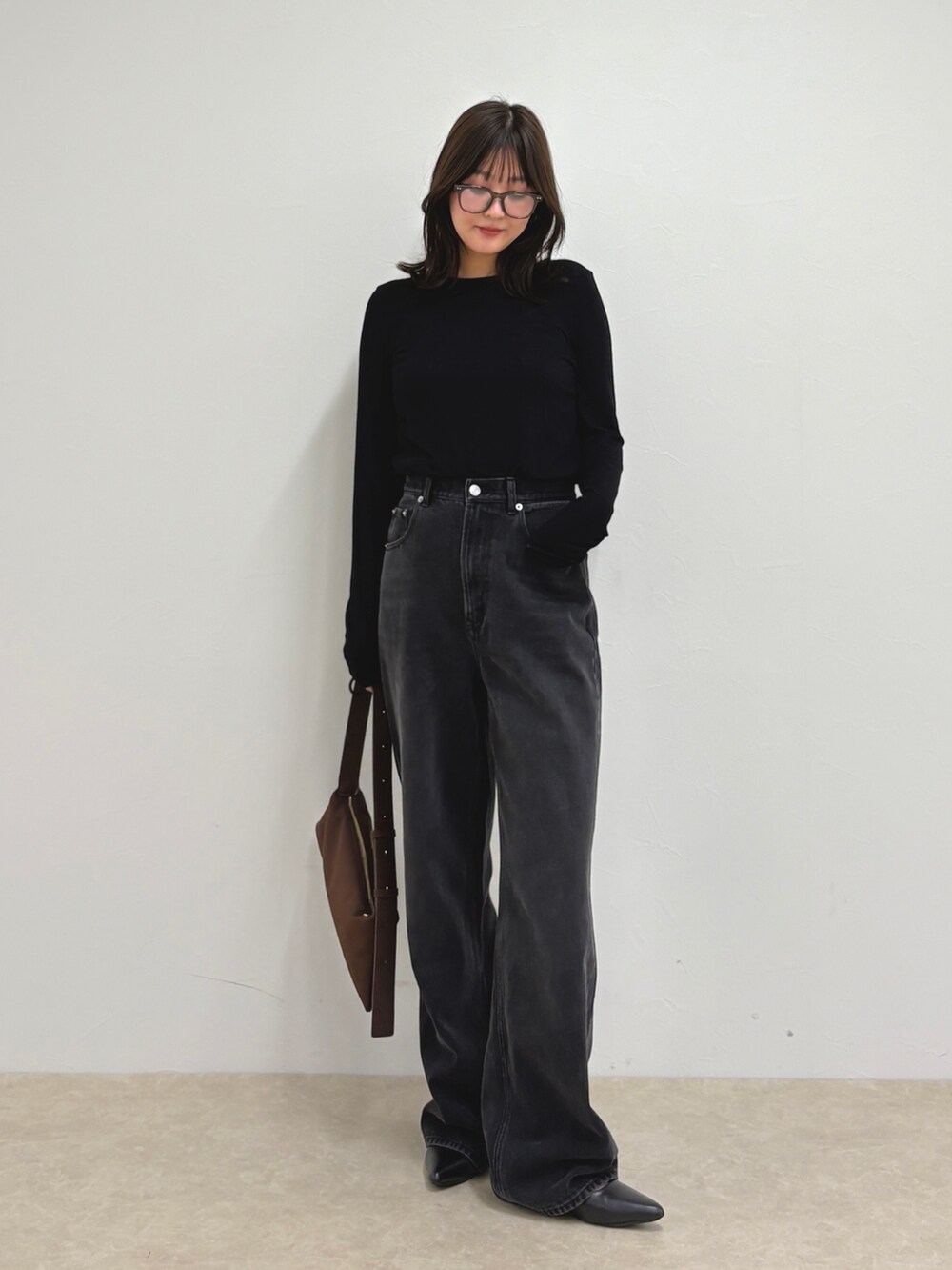 ブルー系のデニムパンツ、ブラック系のTシャツ/カットソー、ブラウン系のショルダーバッグを着用したレディースの夏コーディネートの2枚目の写真