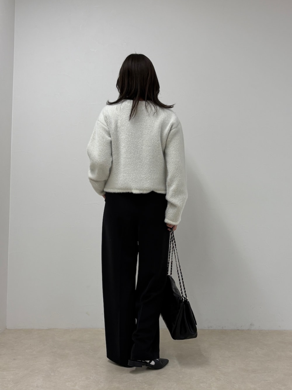 ブラック系のスラックス、ホワイト系のカーディガン/ボレロを着用したレディースの秋コーディネートの2枚目の写真