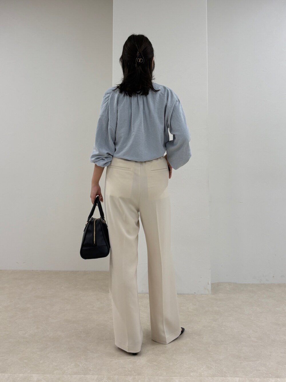 ブルー系のシャツ/ブラウス、ホワイト系のスラックス、ブラック系のショルダーバッグを着用したレディースの秋コーディネートの4枚目の写真