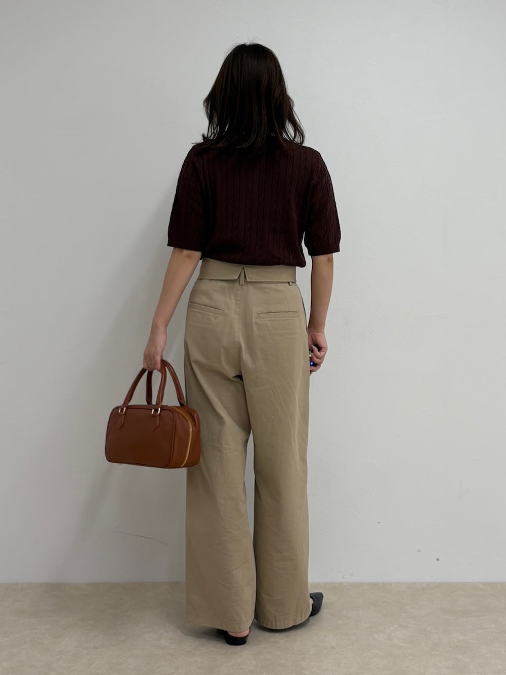 ブラウン系のニット/セーター、ベージュ系のチノパンツ、イエロー系のショルダーバッグを着用したレディースの夏コーディネートの3枚目の写真