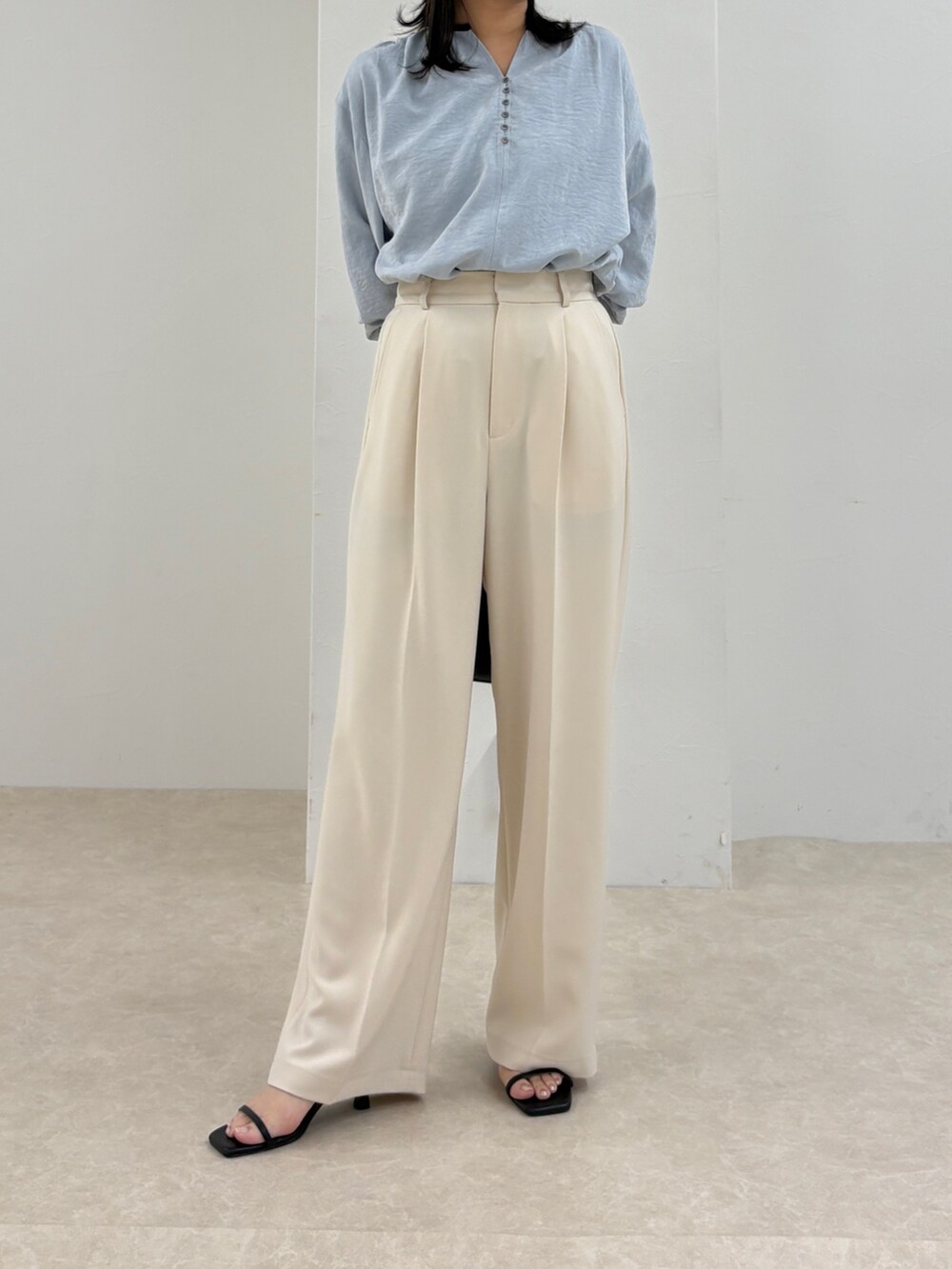 ブルー系のシャツ/ブラウス、ホワイト系のスラックス、ブラック系のショルダーバッグを着用したレディースの秋コーディネートの2枚目の写真