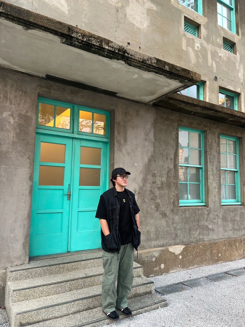 ブラック系のスニーカー、ブラック系のベスト、グリーン系のチノパンツを着用したメンズの秋コーディネートの3枚目の写真