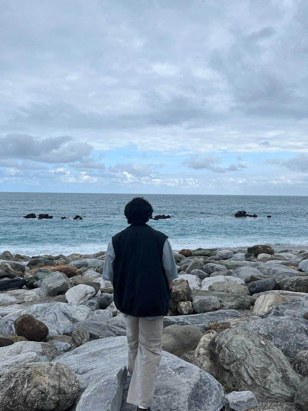 ホワイト系のパンツ、レッド系のローファー、ブラック系のベストを着用したメンズの冬コーディネートの2枚目の写真