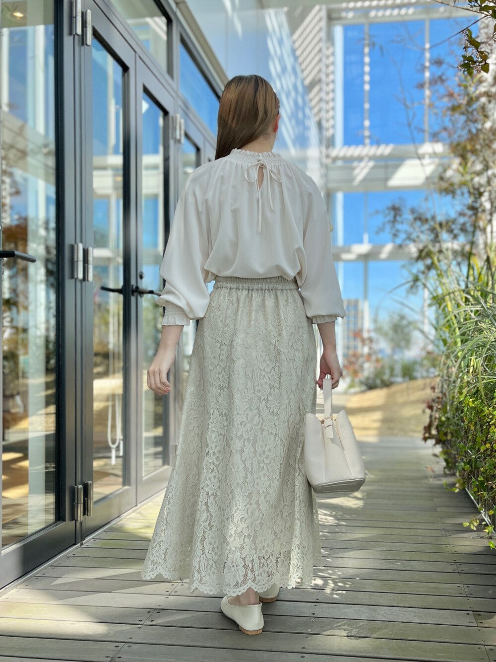ホワイト系のシャツ/ブラウス、グリーン系のスカート、ホワイト系のパンプスを着用したレディースの春コーディネートの3枚目の写真