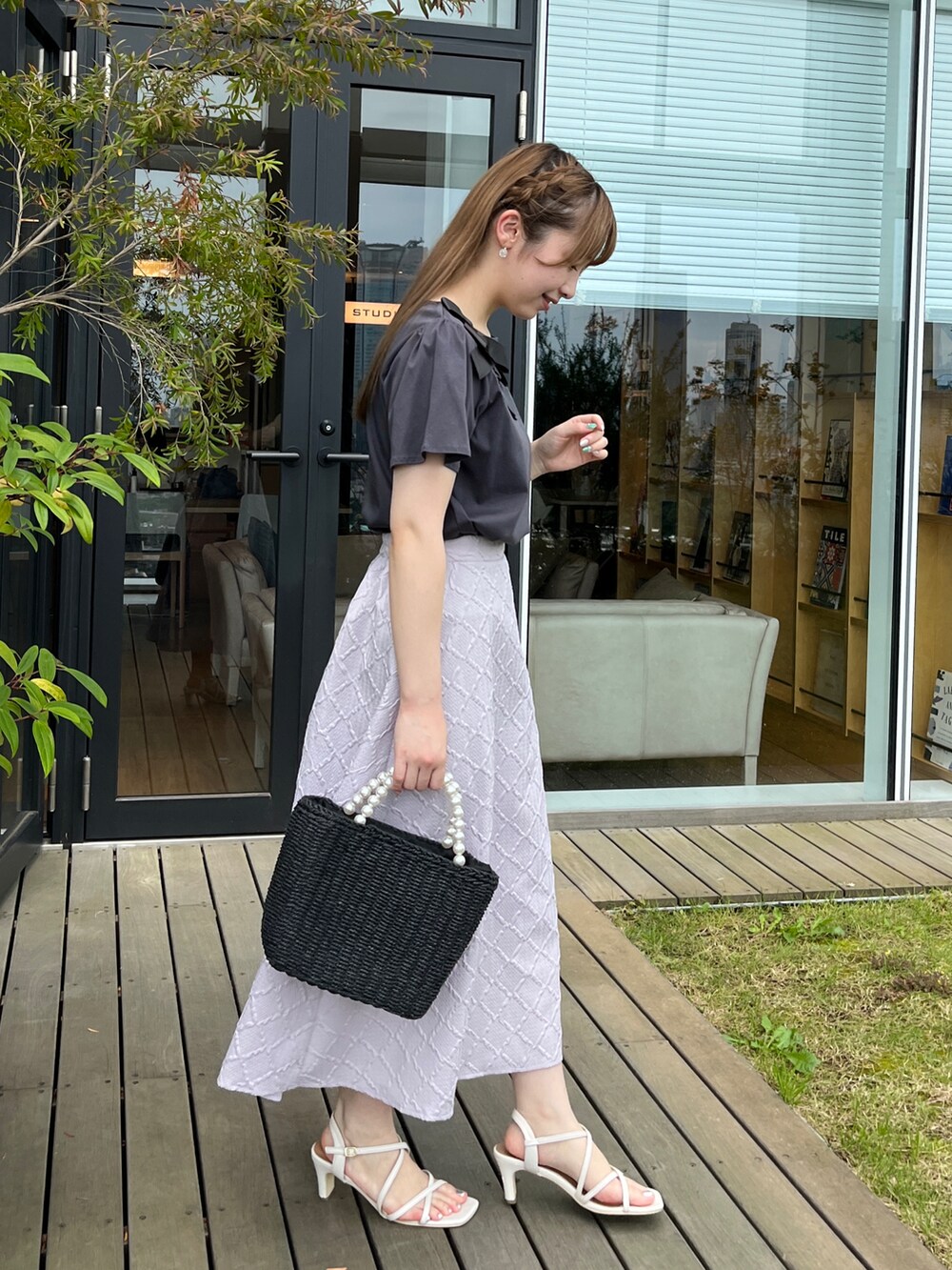 グレー系のTシャツ/カットソー、ブラック系のハンドバッグ、ホワイト系のサンダルを着用したレディースの夏コーディネートの2枚目の写真