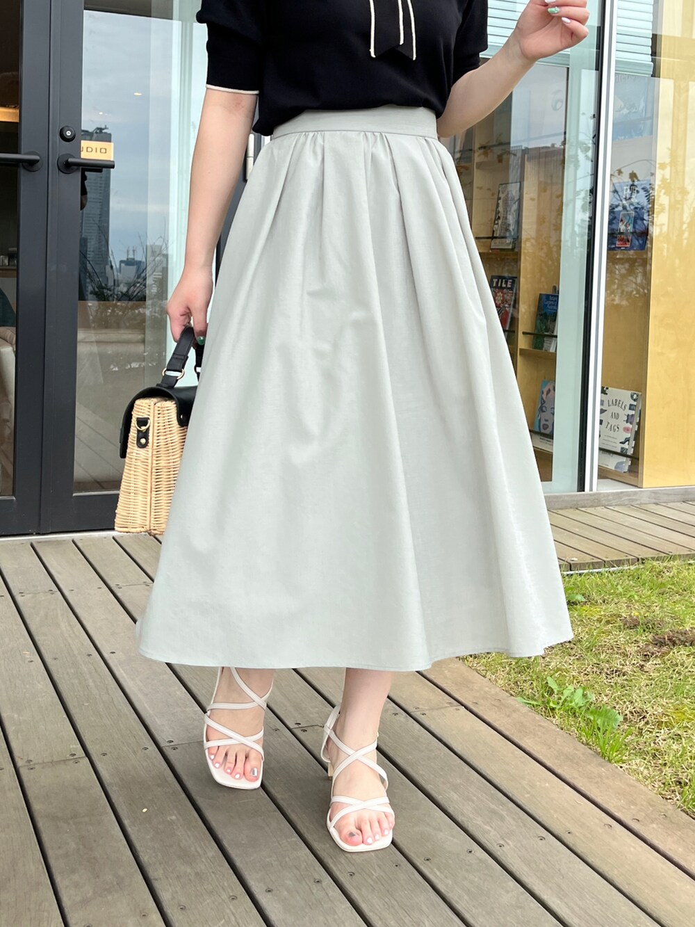 ブラック系のショルダーバッグ、ホワイト系のサンダル、グリーン系のスカートを着用したレディースの夏コーディネートの5枚目の写真