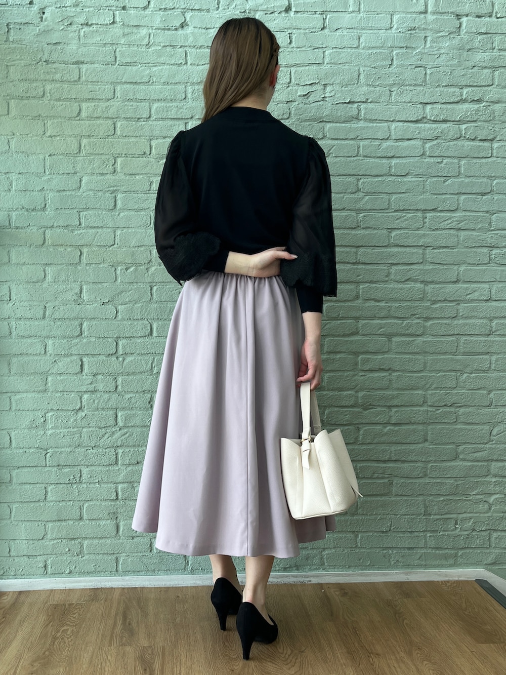 パープル系のスカート、ブラック系のニット/セーター、ブラック系のパンプスを着用したレディースの春コーディネートの3枚目の写真