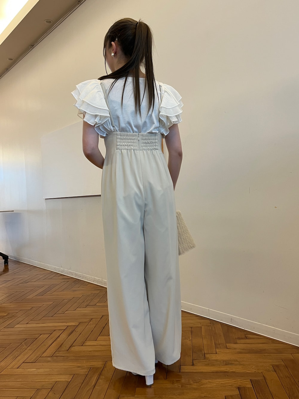 ベージュ系のハンドバッグ、ホワイト系のサンダル、ホワイト系のTシャツ/カットソーを着用したレディースの春コーディネートの3枚目の写真