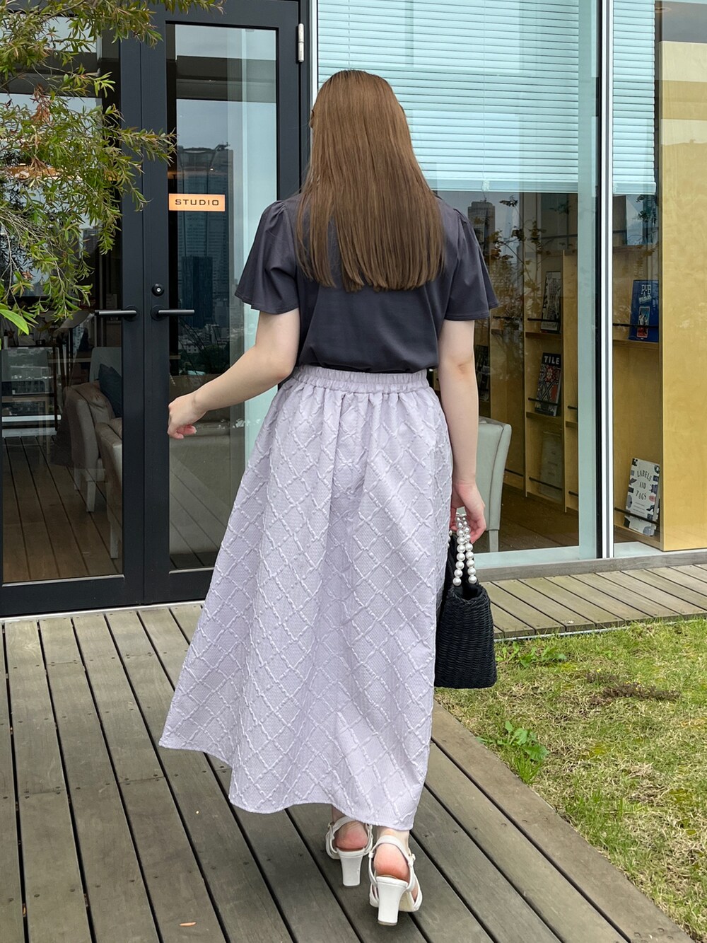 グレー系のTシャツ/カットソー、ブラック系のハンドバッグ、ホワイト系のサンダルを着用したレディースの夏コーディネートの3枚目の写真