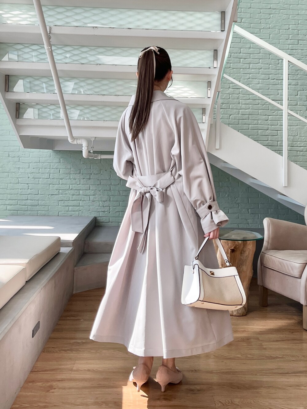 ホワイト系のニット/セーター、ベージュ系のスカート、グレー系のトレンチコートを着用したレディースの冬コーディネートの3枚目の写真