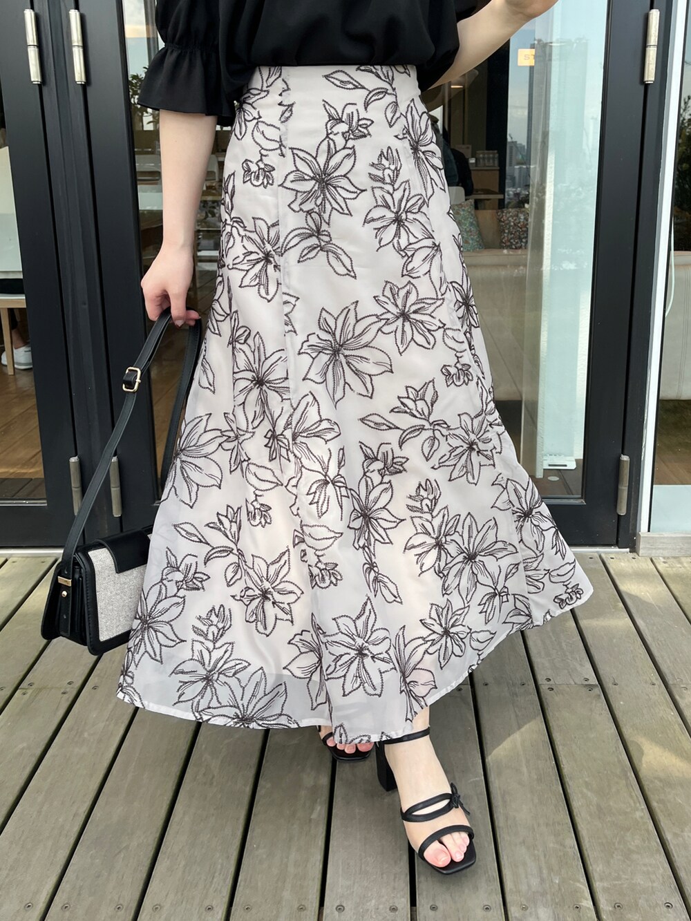 ブラウン系のスカート、ブラック系のシャツ/ブラウスを着用したレディースの夏コーディネートの4枚目の写真