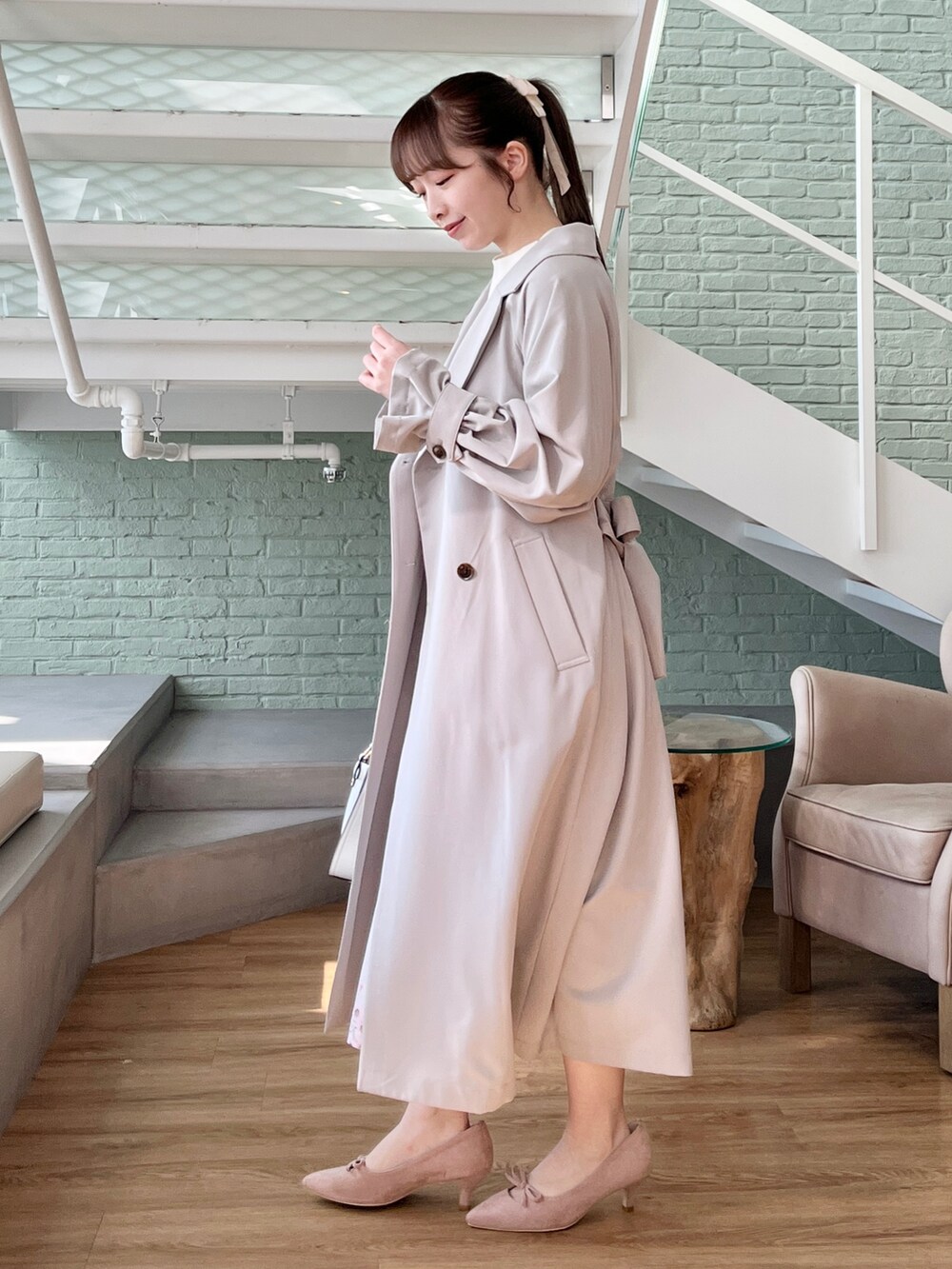 ホワイト系のニット/セーター、ベージュ系のスカート、グレー系のトレンチコートを着用したレディースの冬コーディネートの2枚目の写真