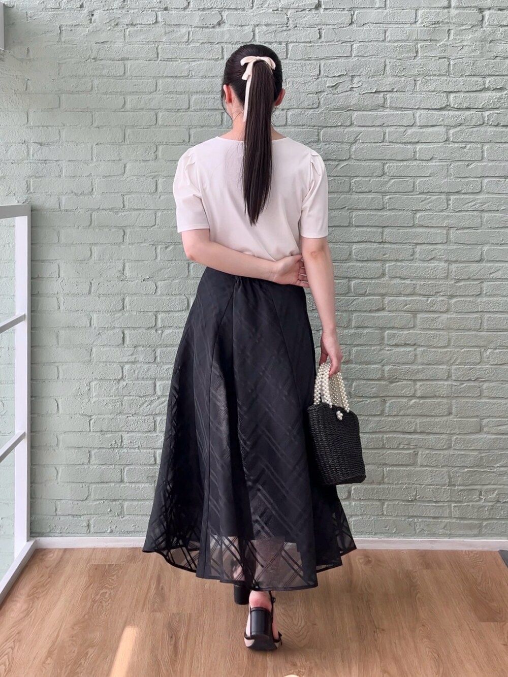 ブラック系のスカート、ホワイト系のTシャツ/カットソーを着用したレディースの夏コーディネートの3枚目の写真