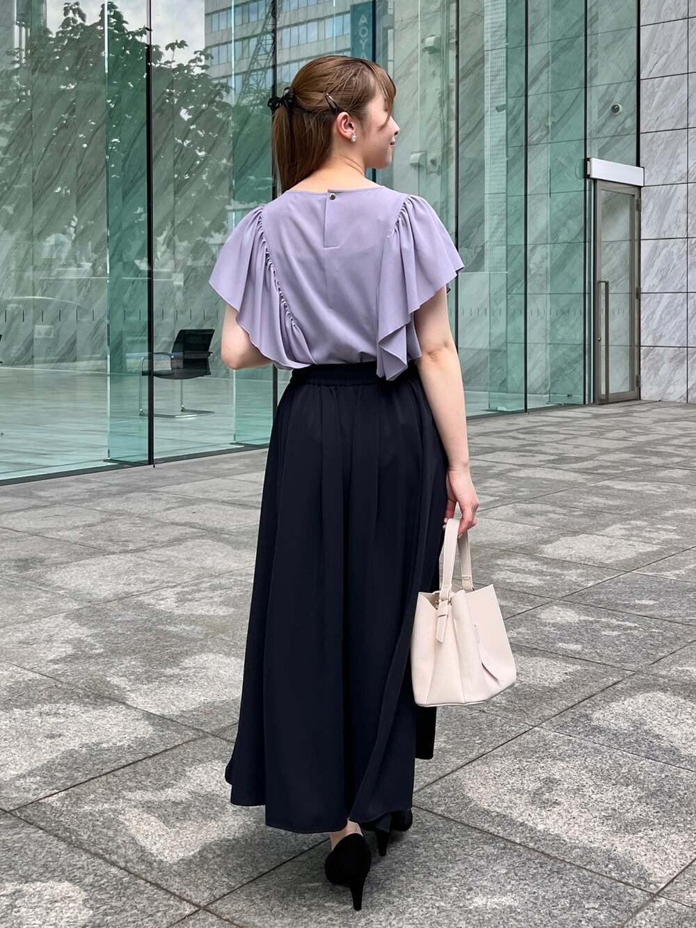 パープル系のシャツ/ブラウス、ホワイト系のショルダーバッグ、ブラック系のパンプスを着用したレディースの夏コーディネートの3枚目の写真