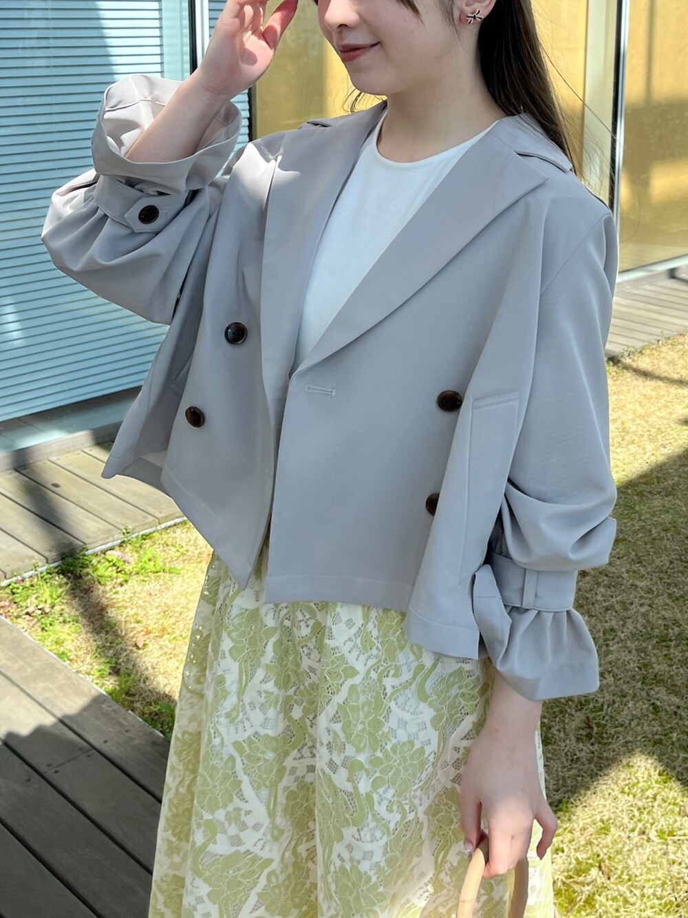 グレー系のトレンチコート、ホワイト系のワンピースを着用したレディースの春コーディネートの4枚目の写真