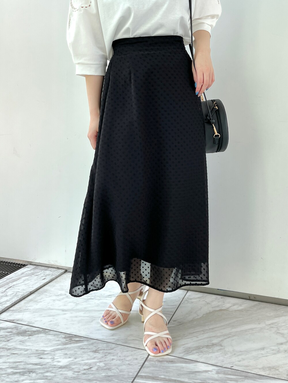 ホワイト系のTシャツ/カットソー、ブラック系のスカート、ホワイト系のサンダルを着用したレディースの春コーディネートの4枚目の写真