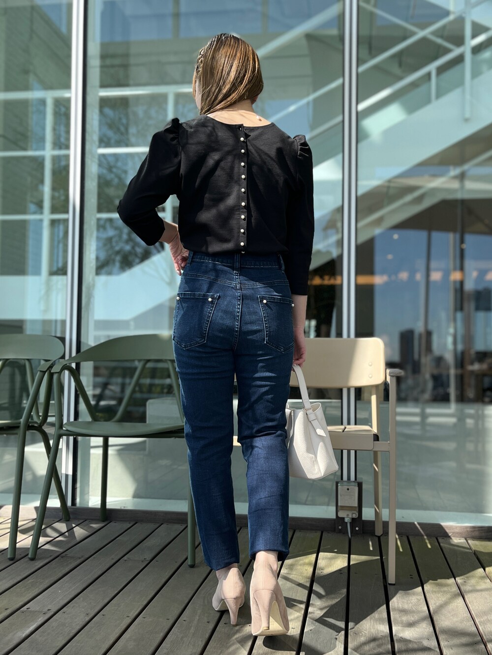 ブルー系のデニムパンツ、ブラック系のTシャツ/カットソー、ベージュ系のパンプスを着用したレディースの春コーディネートの3枚目の写真