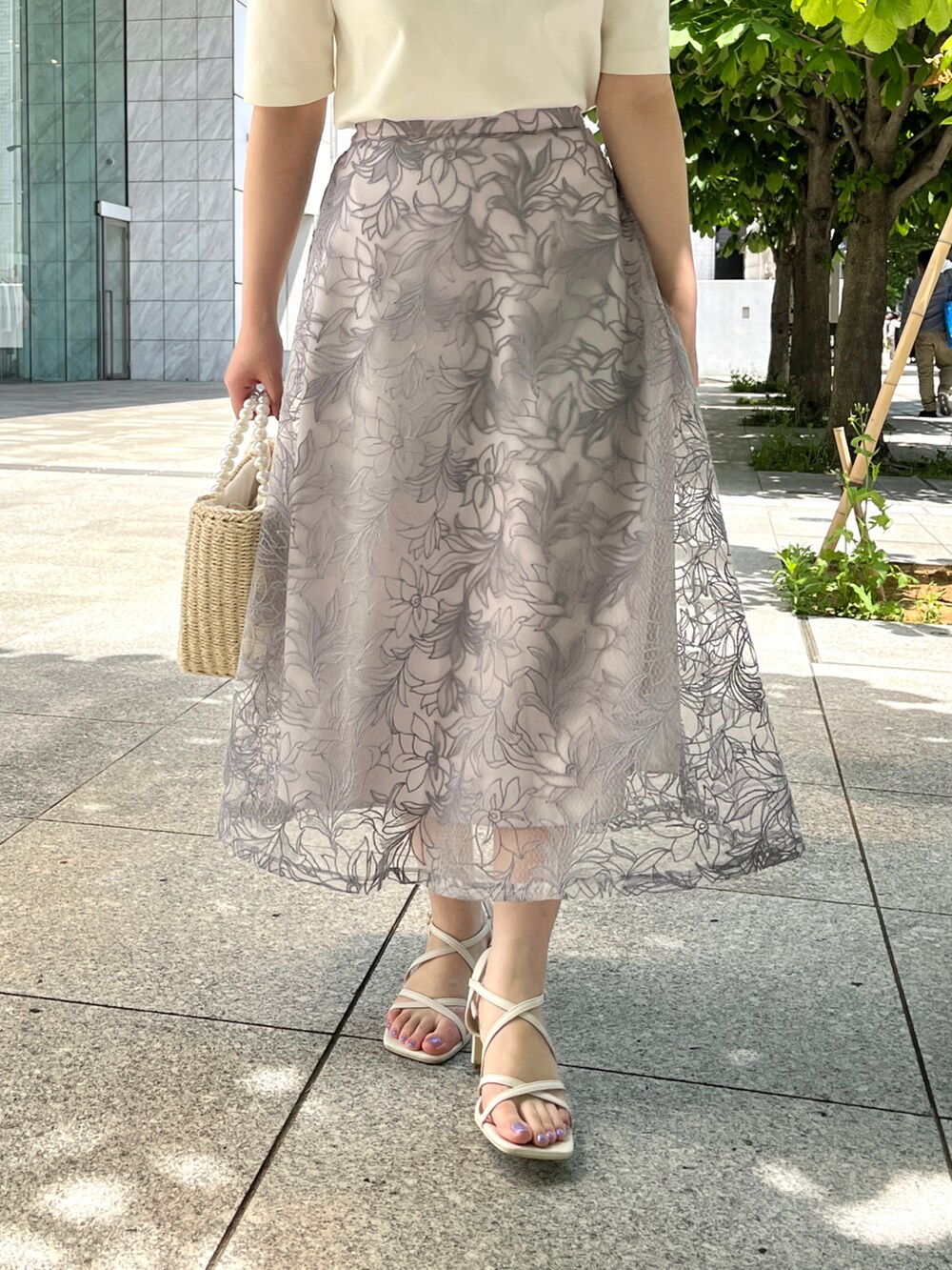 ホワイト系のTシャツ/カットソー、ブルー系のスカート、ベージュ系のハンドバッグを着用したレディースの夏コーディネートの3枚目の写真