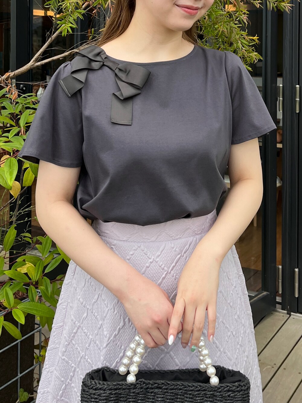 グレー系のTシャツ/カットソー、ブラック系のハンドバッグ、ホワイト系のサンダルを着用したレディースの夏コーディネートの4枚目の写真