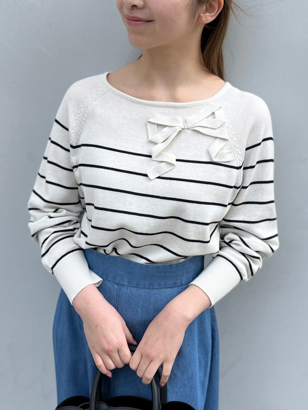 ホワイト系のニット/セーター、ブルー系のスカート、ブラック系のショルダーバッグを着用したレディースの冬コーディネートの4枚目の写真