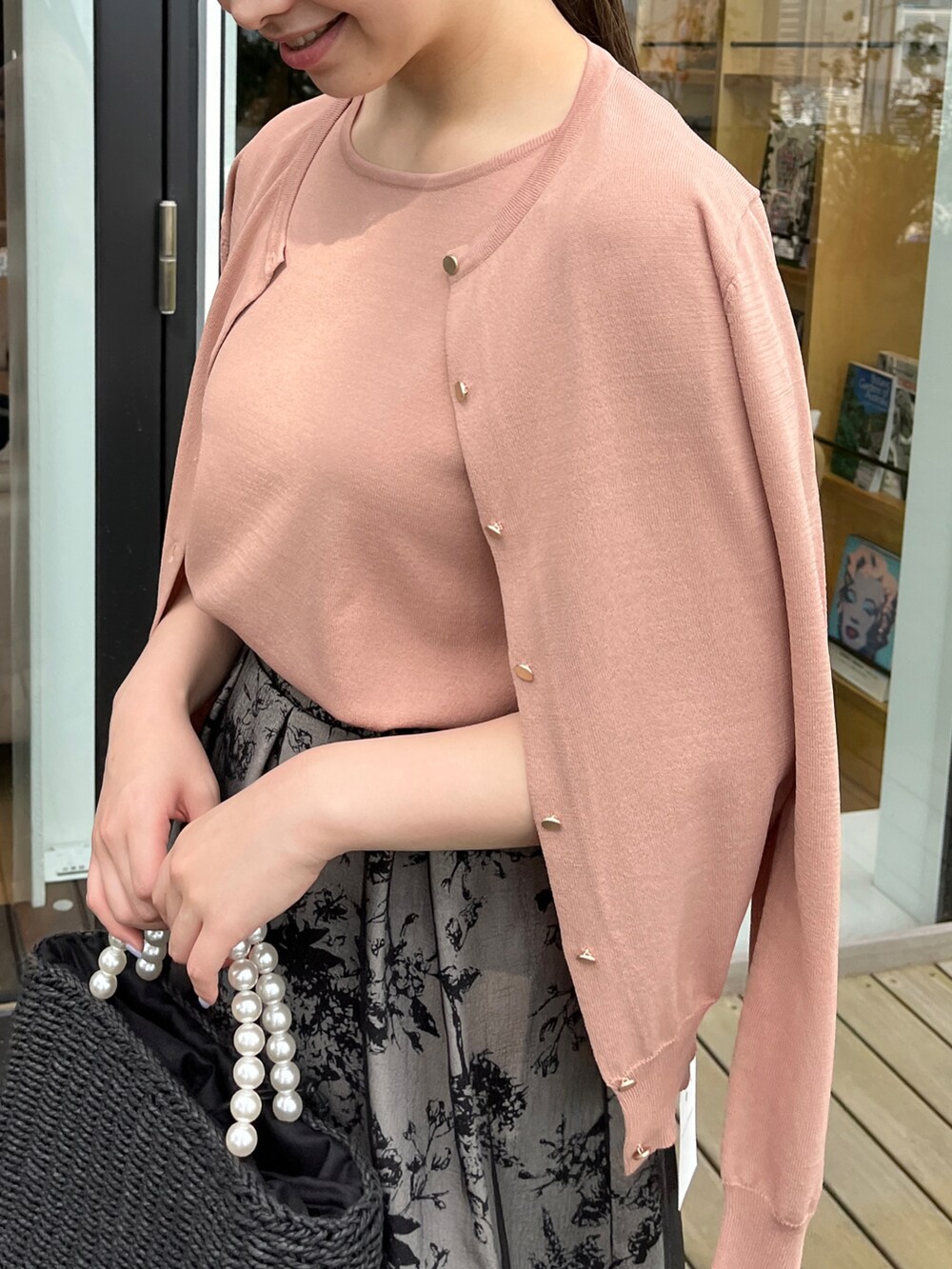 ブラック系のハンドバッグ、ブラック系のサンダル、ピンク系のニット/セーターを着用したレディースの夏コーディネートの2枚目の写真