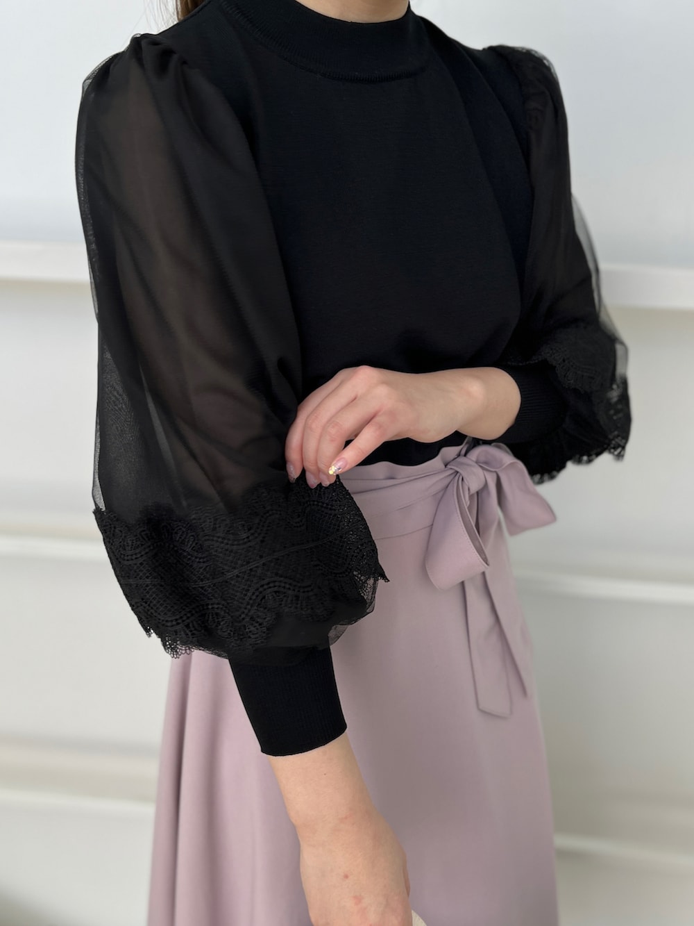 パープル系のスカート、ブラック系のニット/セーター、ブラック系のパンプスを着用したレディースの春コーディネートの4枚目の写真