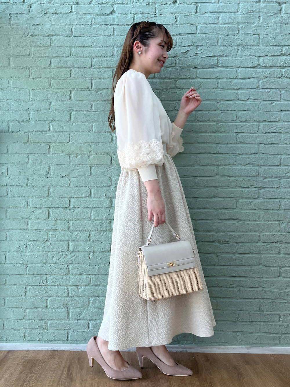 ベージュ系のスカート、ホワイト系のニット/セーター、グレー系のショルダーバッグを着用したレディースの春コーディネートの2枚目の写真