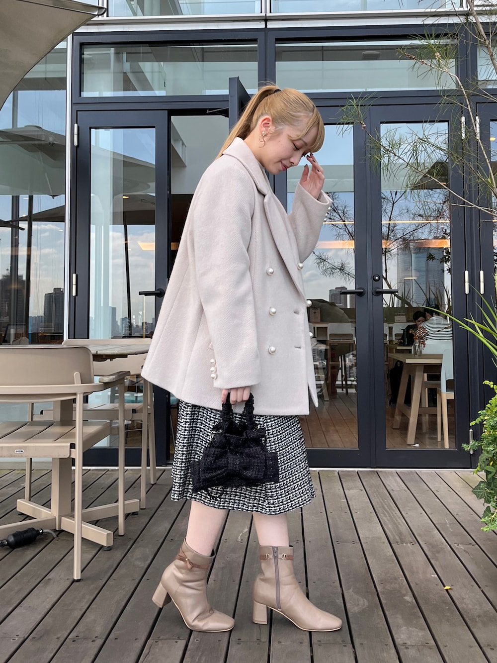 ベージュ系のピーコート、ブラック系のワンピースを着用したレディースの冬コーディネートの2枚目の写真